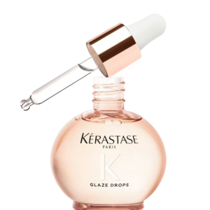 A round bottle labeled “Kérastase Paris K Glaze Drops” with a gold-topped dropper resting on its opening, designed to deliver hair shine and reveal a radiant Gloss Absolu finish. | Blush Salon Collective - Fargo, ND