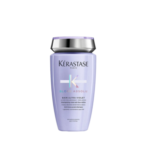 A bottle of Kérastase Blond Absolu Bain Ultra-Violet shampoo, featuring a lavender color with a silver cap, designed for blonde or gray hair as part of the Blond Absolu hair care range, shown on a plain white background. | Blush Salon Collective - Fargo, ND