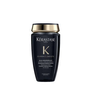 A bottle of Kérastase Paris Chronologiste Bain Regenerant shampoo, a luxurious hair care essential with gold and black packaging, displayed on a plain white background. | Blush Salon Collective - Fargo, ND