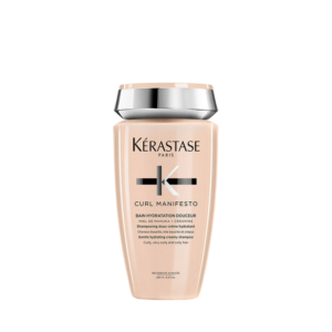 Beige bottle of Kérastase Curl Manifesto Bain Hydration Douceur shampoo for curly, very curly, and coily hair, with a silver cap, on a plain white background. This nourishing Bain Hydration formula from the Curl Manifesto line gently cleanses while enhancing softness and definition. | Blush Salon Collective - Fargo, ND