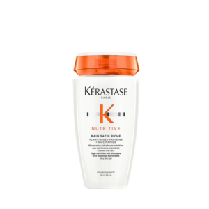 A white bottle of Kérastase Nutritive Bain Satin Riche shampoo with an orange cap, displayed against a plain white background, highlights premium hair care for nourished and revitalized locks. | Blush Salon Collective - Fargo, ND