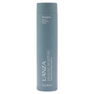 A tall, cylindrical bottle of L’ANZA Healing Moisture Moisturizing Shampoo with a gray cap and label stands upright against a white background. | Blush Salon Collective - Fargo, ND